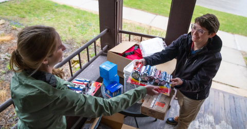 Kirsten Alman unpacks medical supplies on the porch of the Healing House and hands them to Christina Hughey